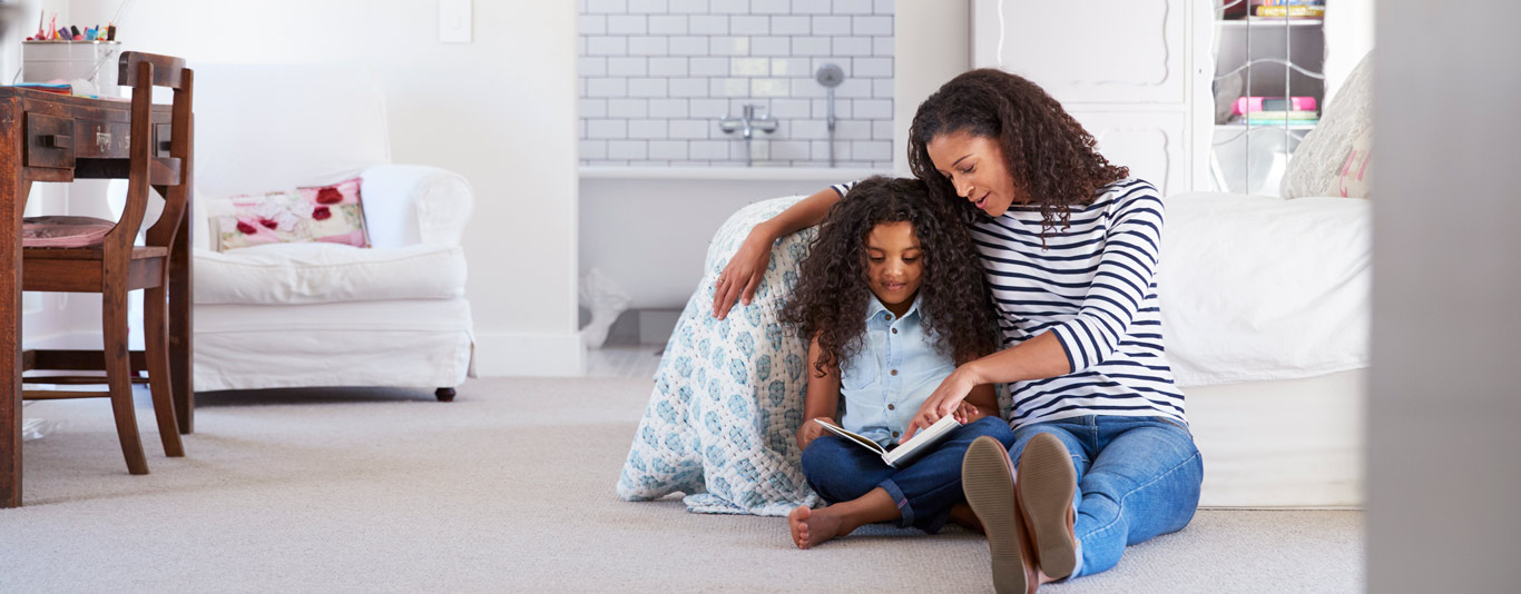 Mom and daughter reading by a bed